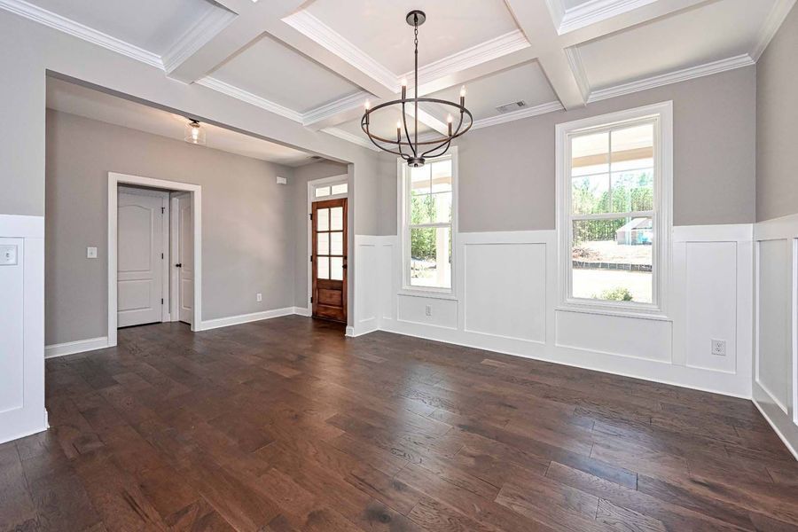 Spacious dining room with hardwood floors, gray walls, white trim, and a chandelier.
