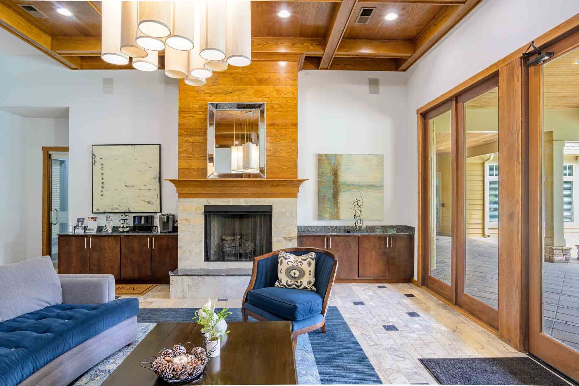 Luxurious living room with fireplace, blue sofa, wood accents, and glass doors at Ansley Falls Apartment Homes in Charlotte, NC.