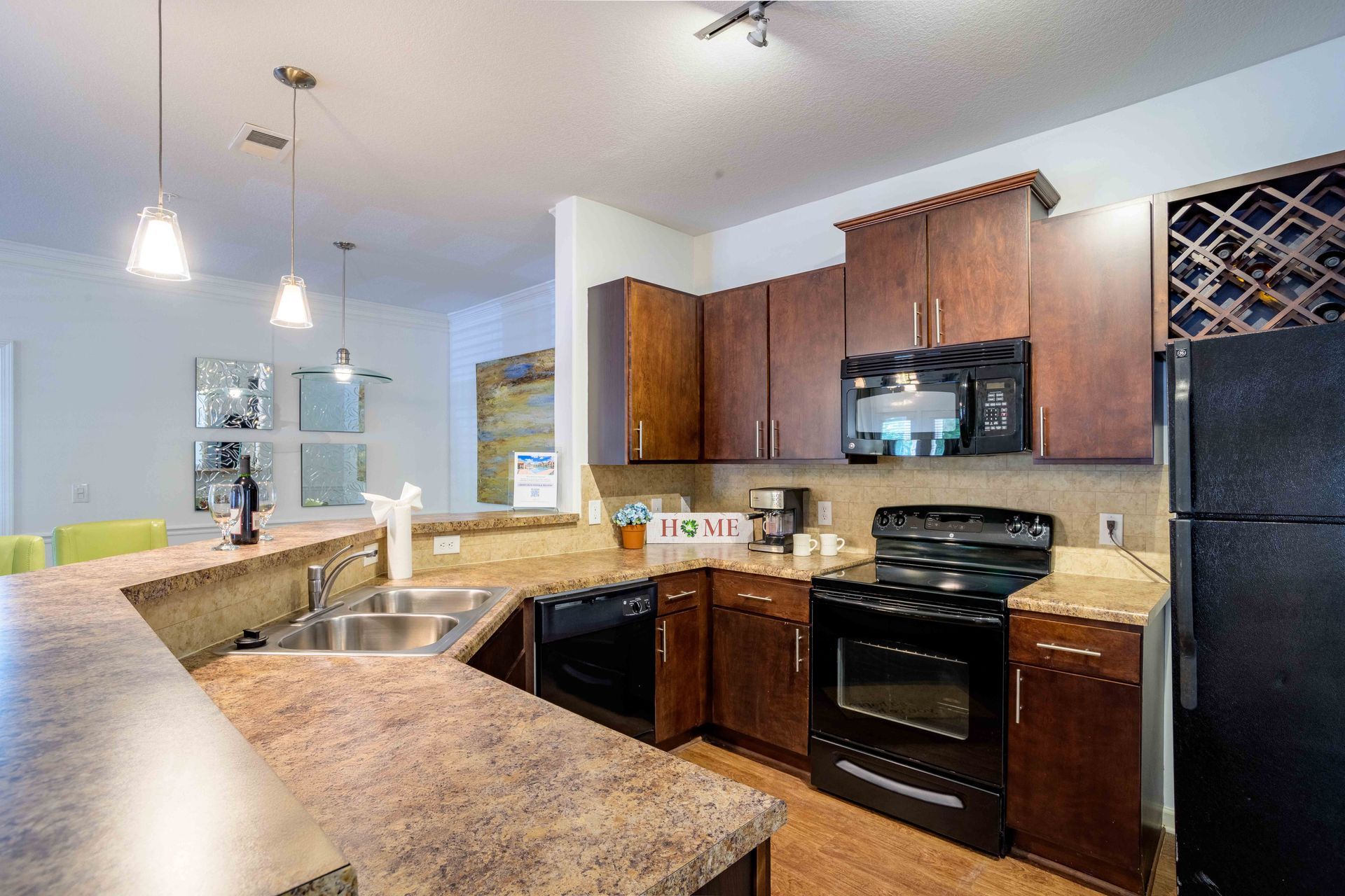 Kitchen with dark wood cabinets, appliances, and countertop. A view of an open floor plan at Ansley Falls Apartment Homes in Charlotte, NC.