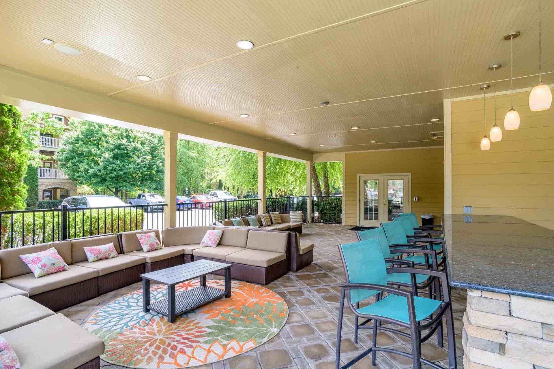 Outdoor lounge area with seating, bar, and colorful rug at Ansley Falls Apartment Homes in Charlotte, NC.