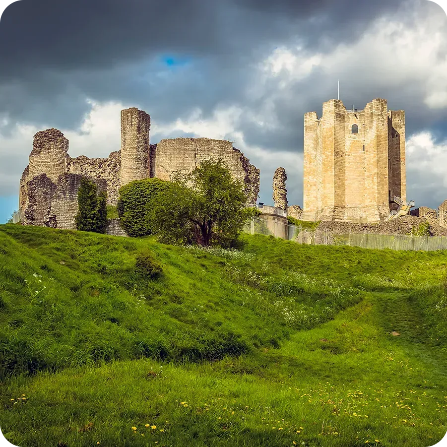 A castle is sitting on top of a grassy hill.