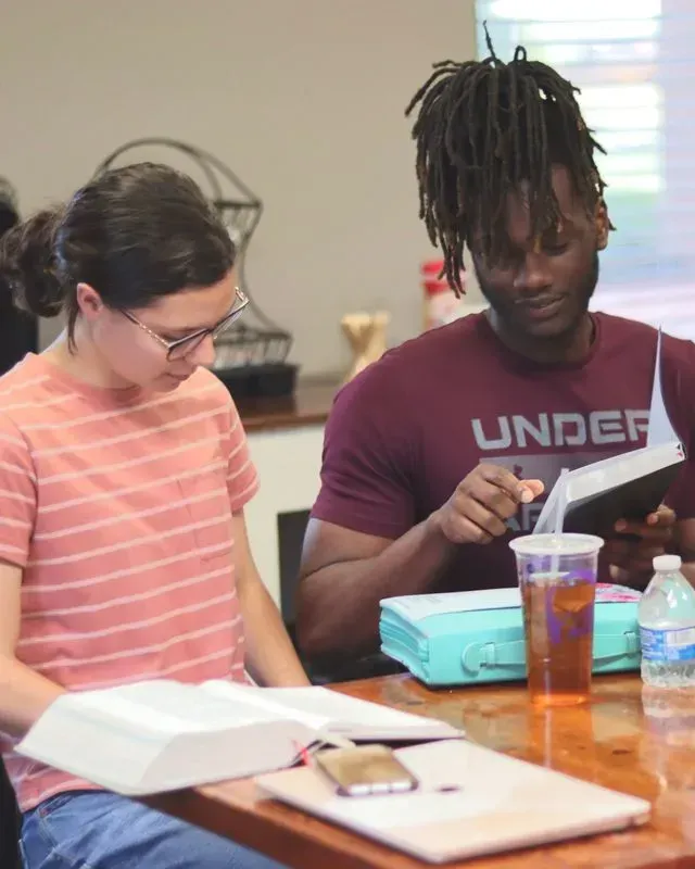 A man in an under armour shirt is reading a book