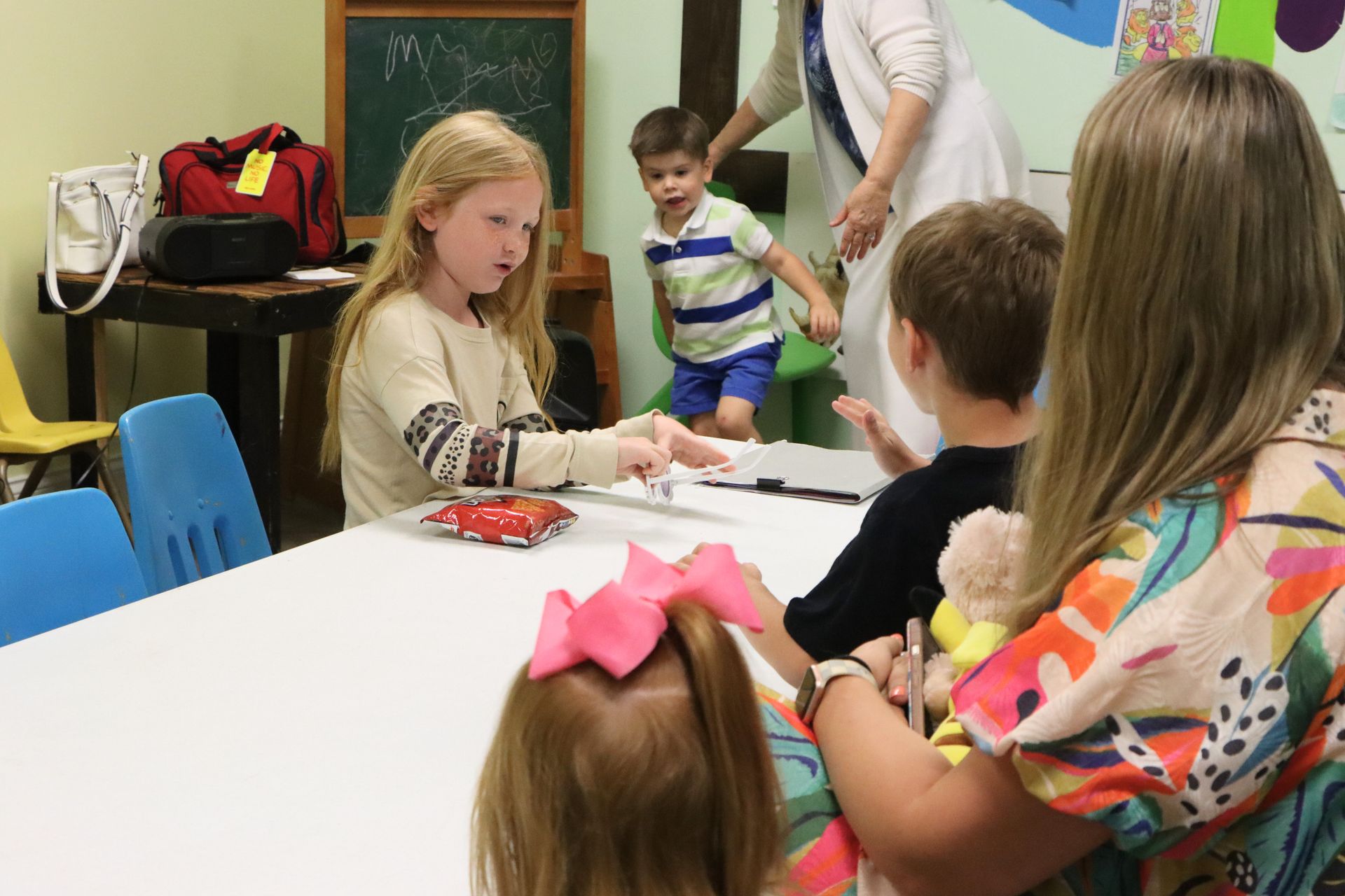 A woman is sitting at a table with a group of children.