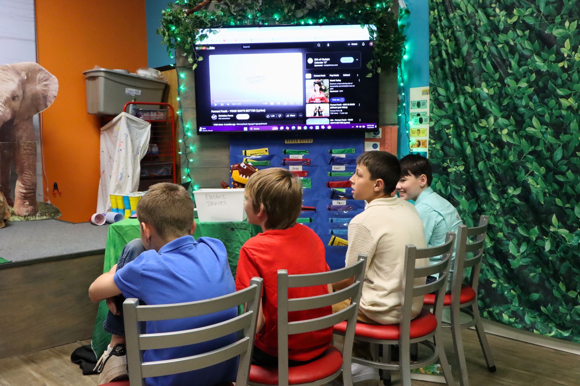 A group of young boys are sitting in front of a television.