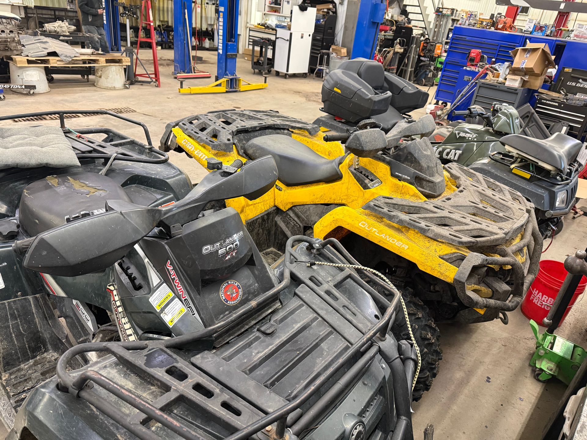 Rows of yellow and black ATVs inside a repair garage | Itasca Automotive in Bigfork, MN