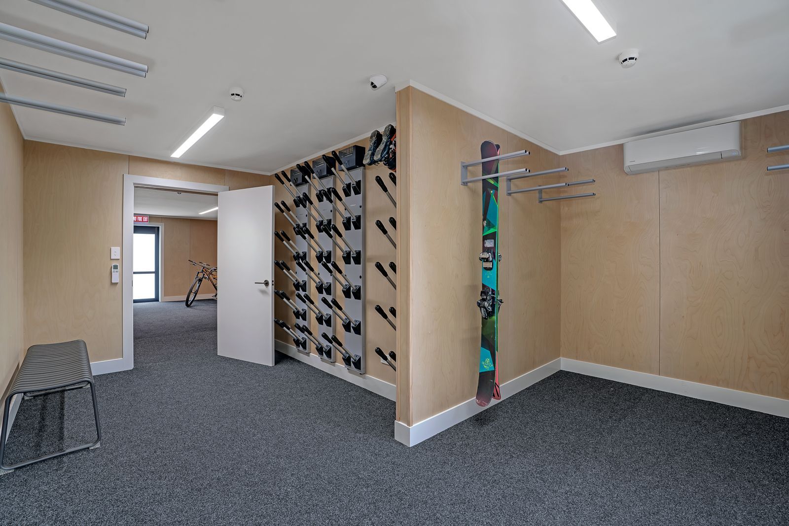 A bunch of skis are lined up on a rack in a room.
