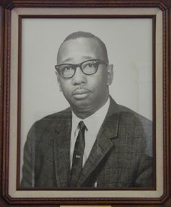 Man in suit and glasses, posed portrait in a framed picture.