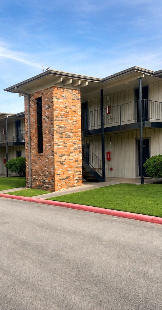 Courtyard flower bed with stepping stones, bushes, and a flagpole between brick buildings