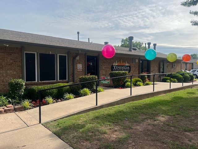 Brick building entrance with colorful balloons along a ramp and walkway outside.