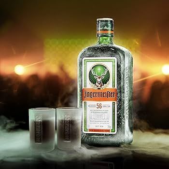 A bottle of jagermeister is sitting next to two shot glasses.