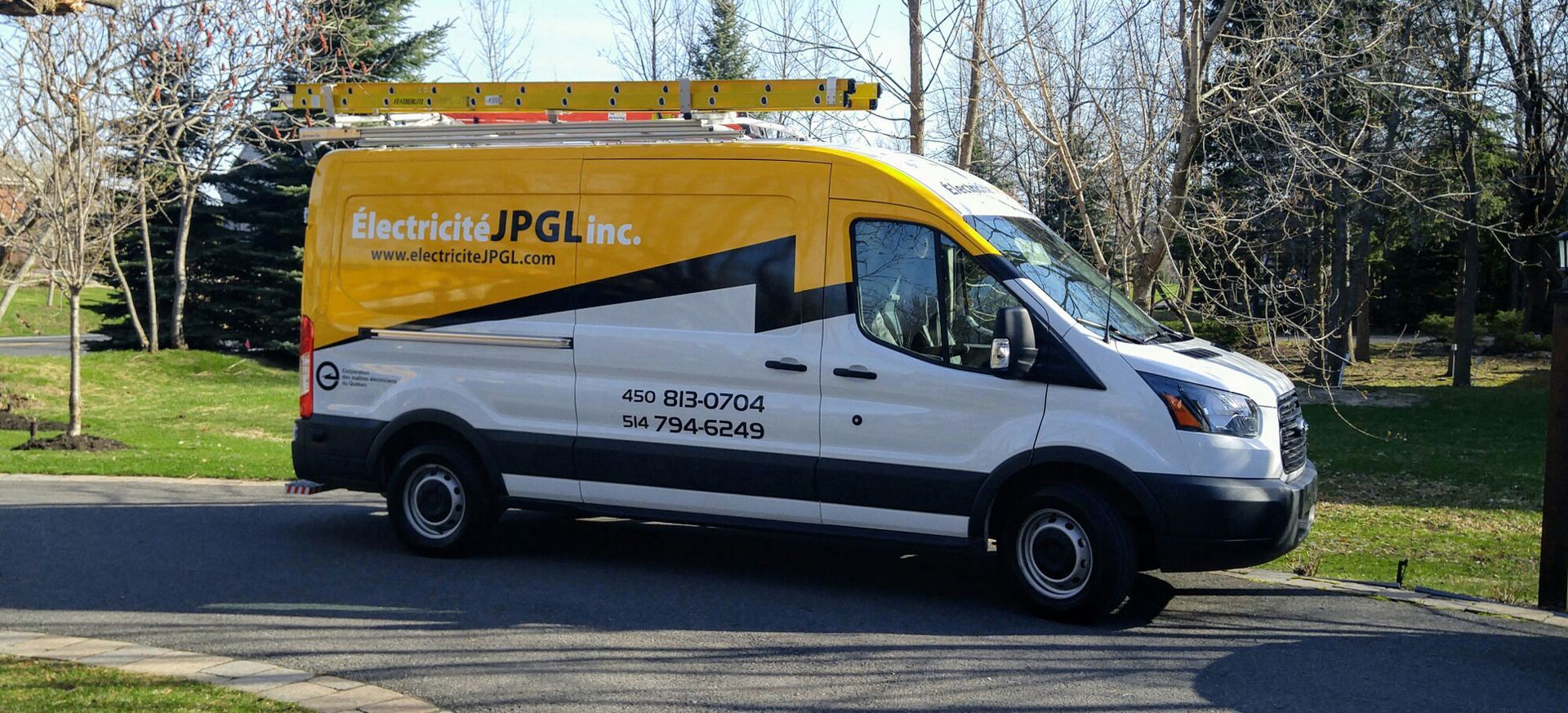 Une camionnette blanche et jaune est garée sur le bord de la route.