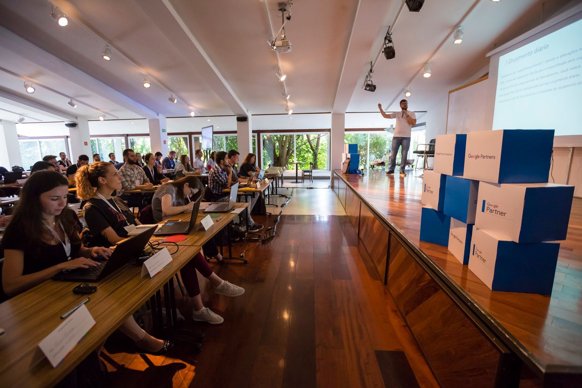 Instrutor Daniel Santos fazendo um treinamento de Google Analytics para um grande grupo de pessoas em um auditório
