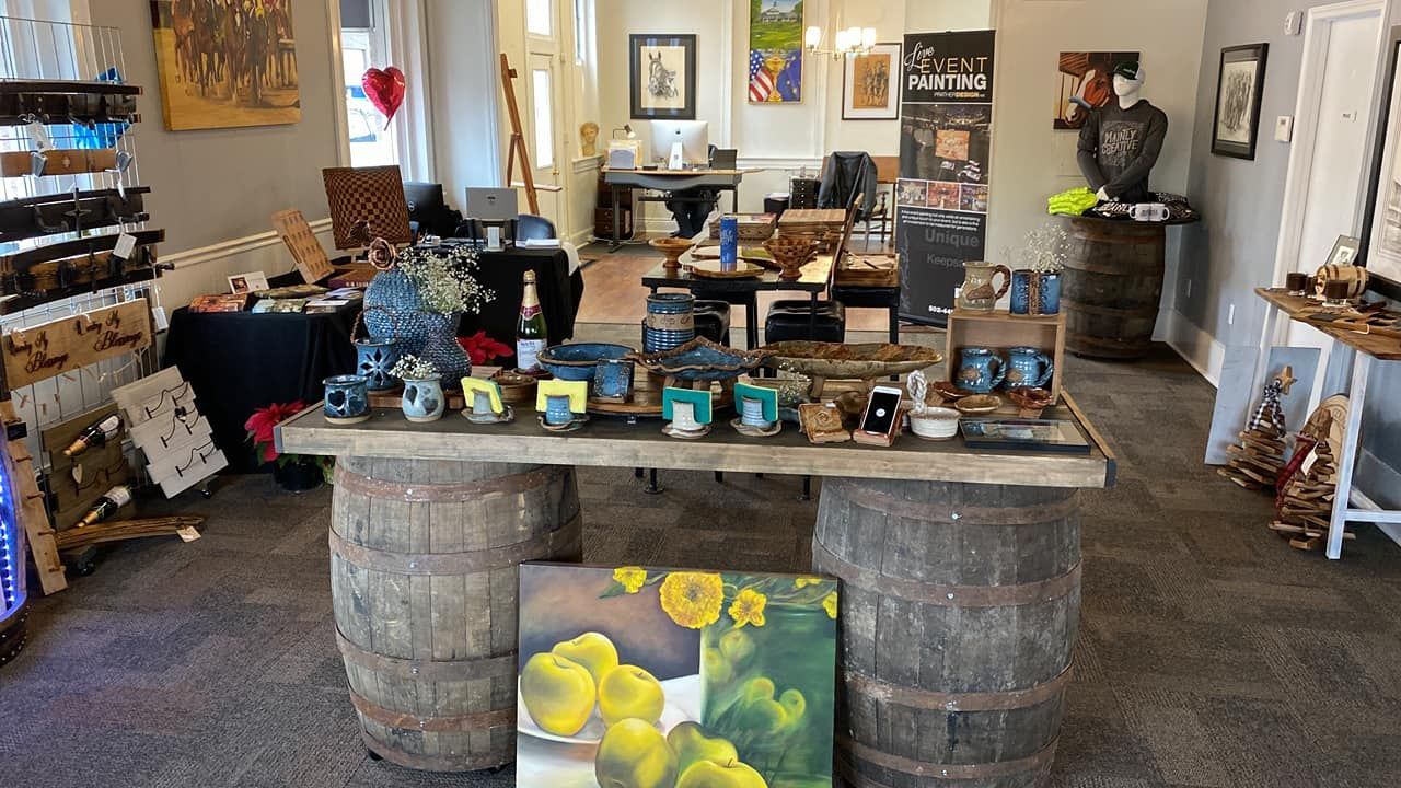 A room with barrels and a table with a painting of sunflowers on it.
