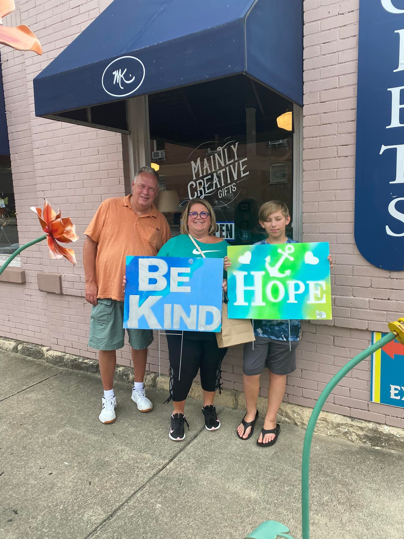 A group of people are holding signs that say `` be kind and hope ''.