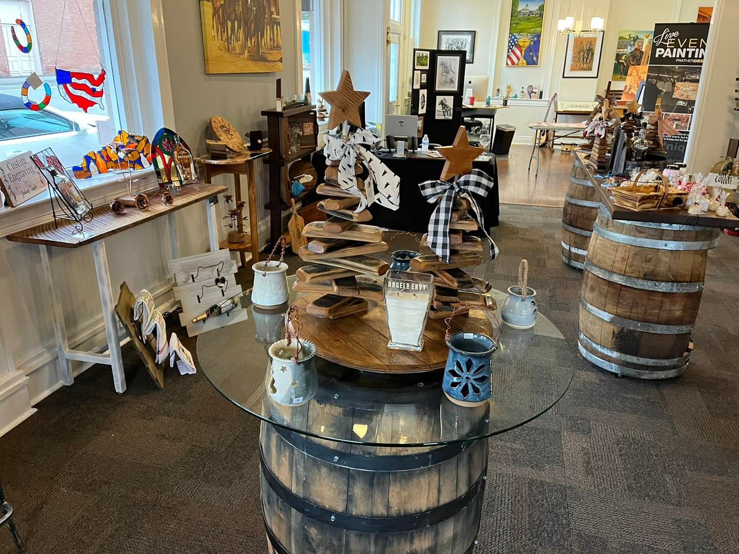 A glass table is sitting on top of a wooden barrel in a store.