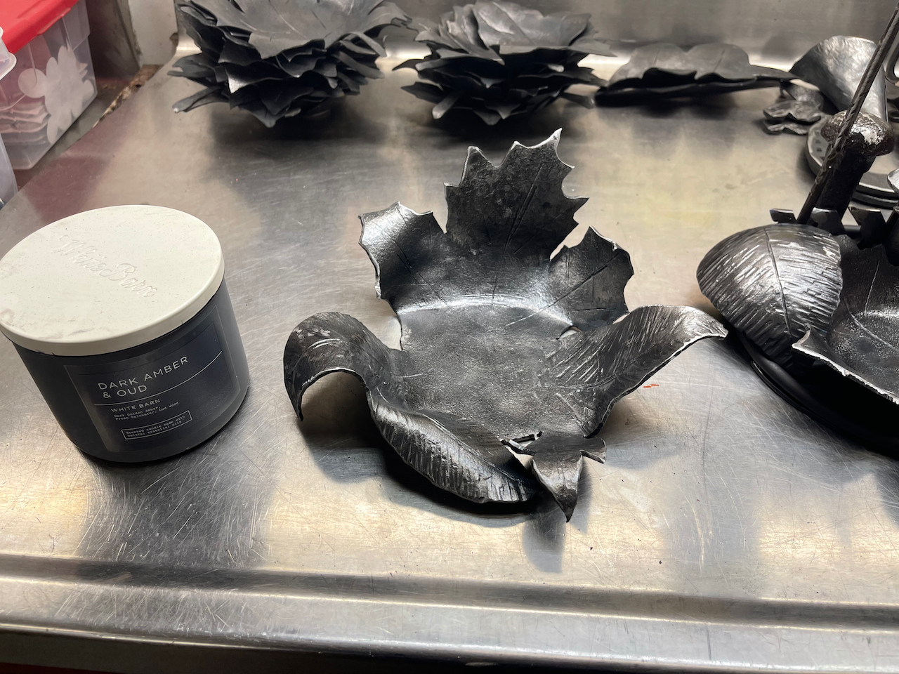 A metal sculpture is sitting on a stainless steel counter next to a jar.