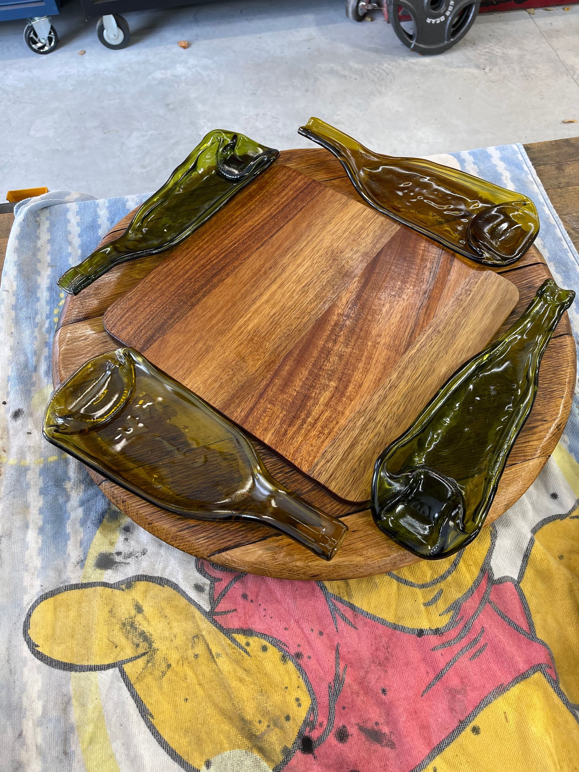 A wooden cutting board with glass bottles on it is sitting on a winnie the pooh towel.