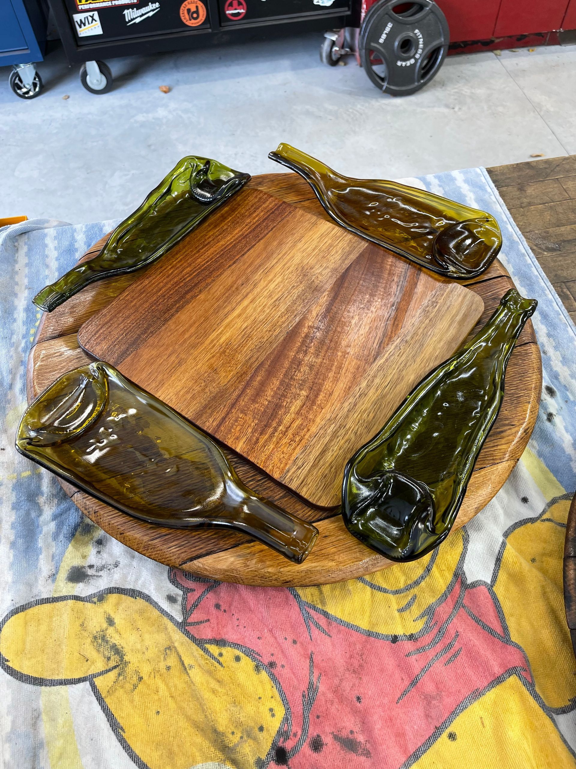 A wooden cutting board with glass bottles on it is sitting on a winnie the pooh towel.