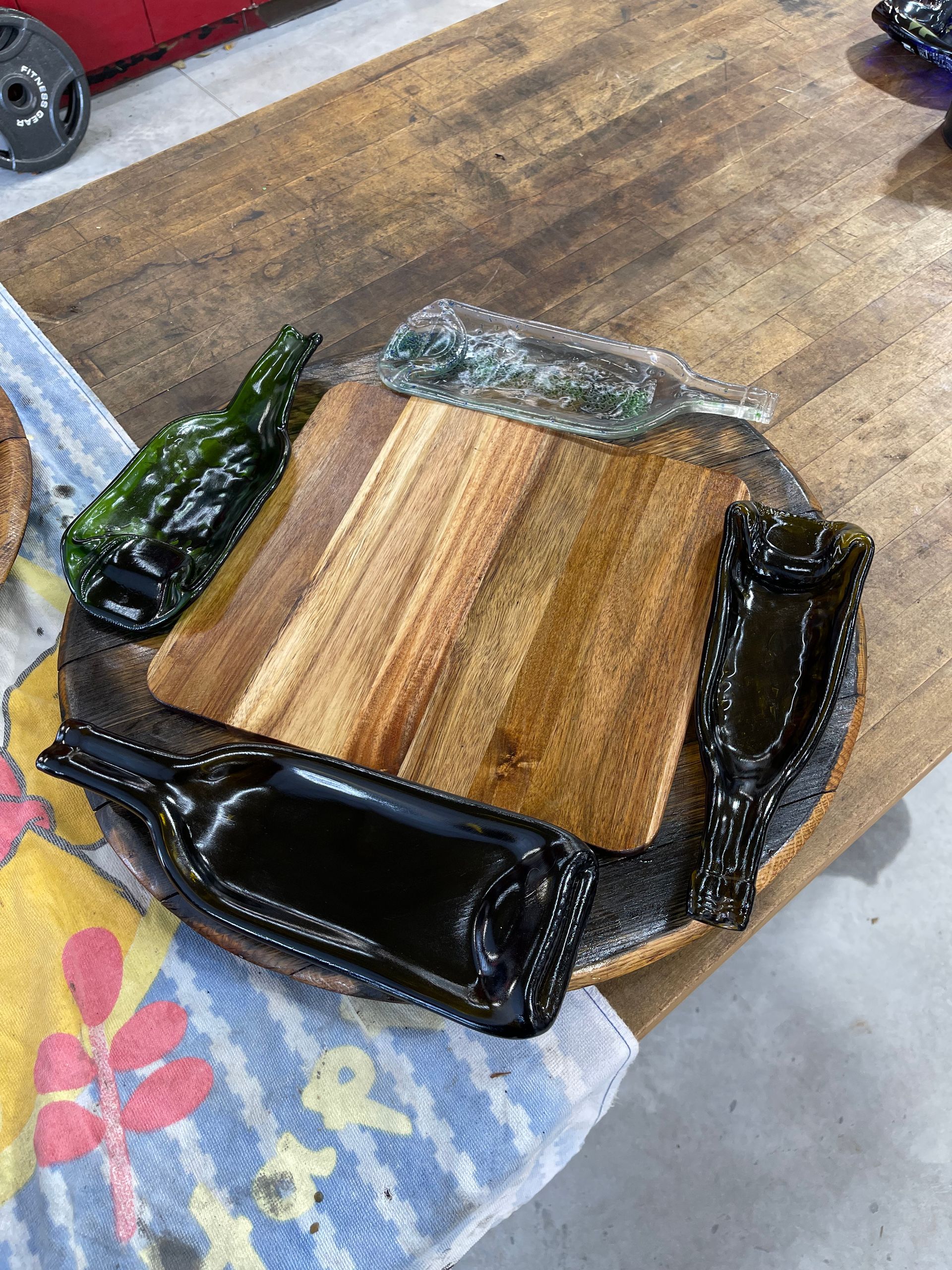 A wooden cutting board with bottles on it is sitting on a wooden table.