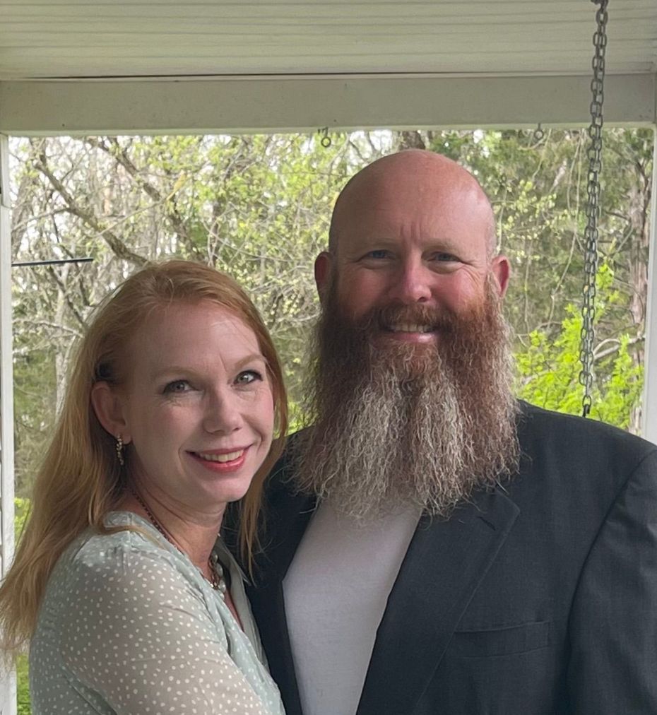 A man with a beard and a woman are posing for a picture on a porch.