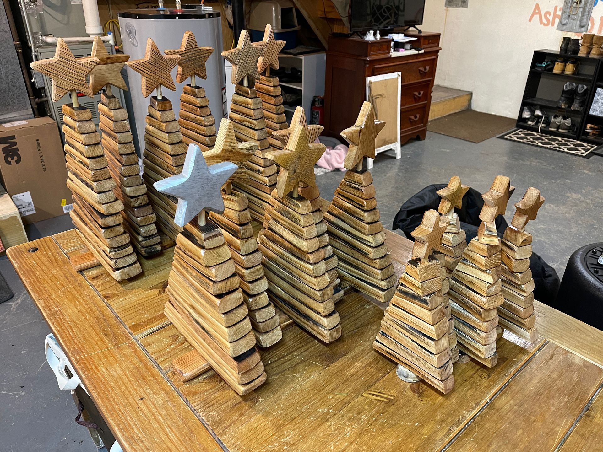 A table topped with a bunch of wooden christmas trees with stars on top.