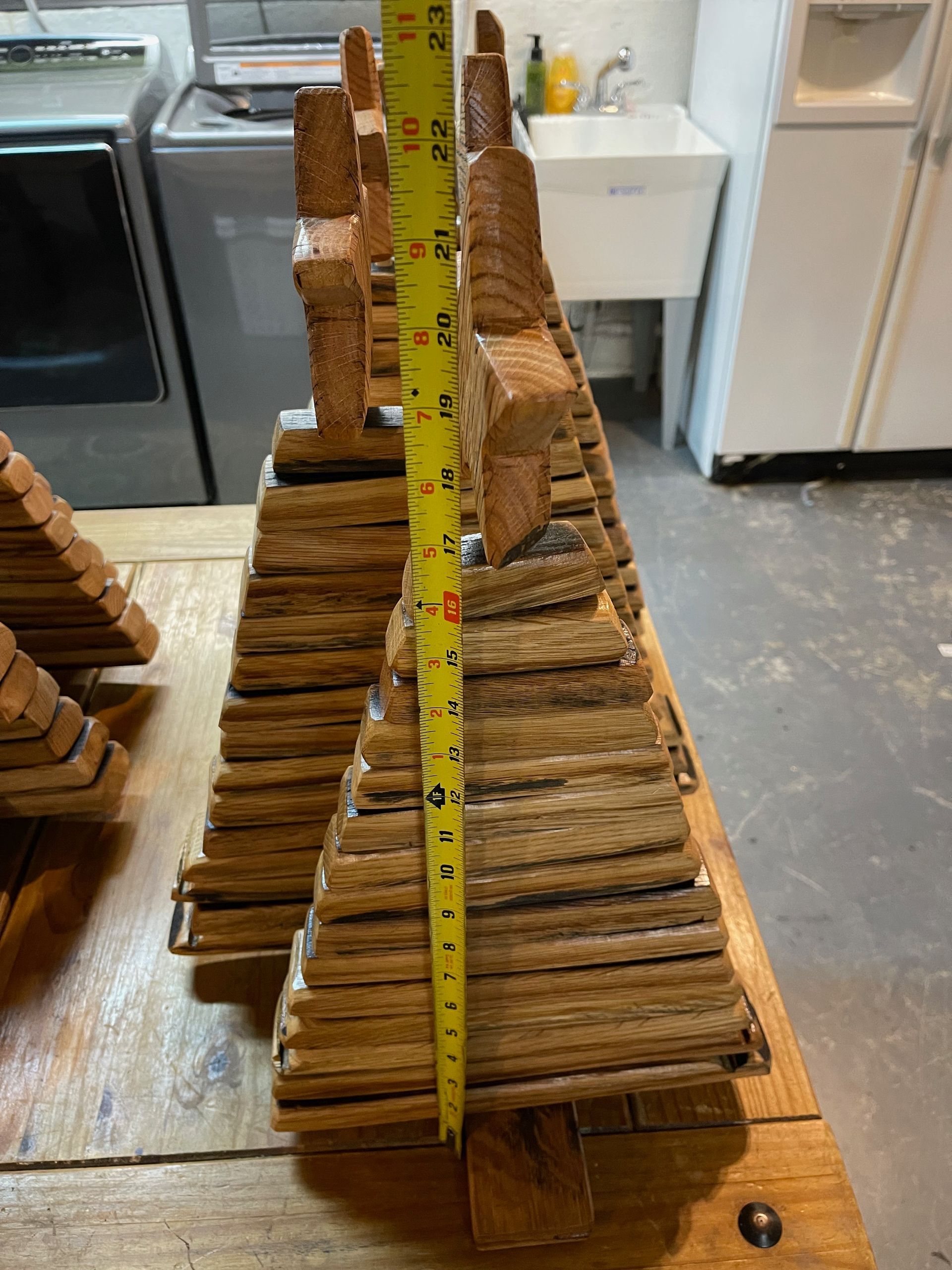 A wooden sculpture is being measured with a tape measure.
