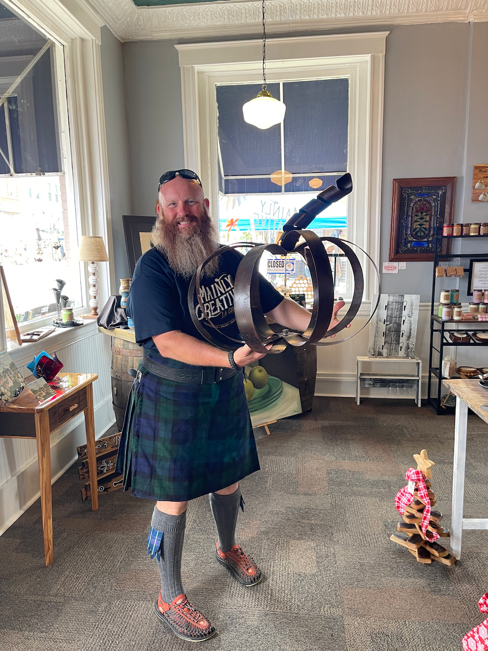 A man in a kilt is holding a sculpture in a room.