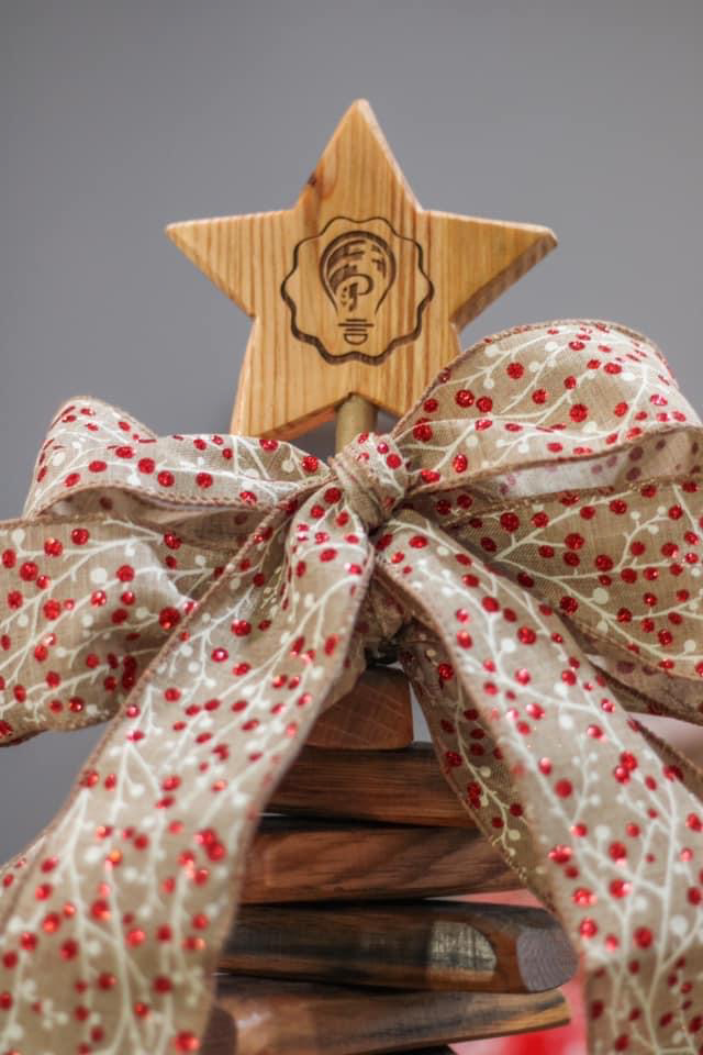 A wooden christmas tree with a star on top and a bow.