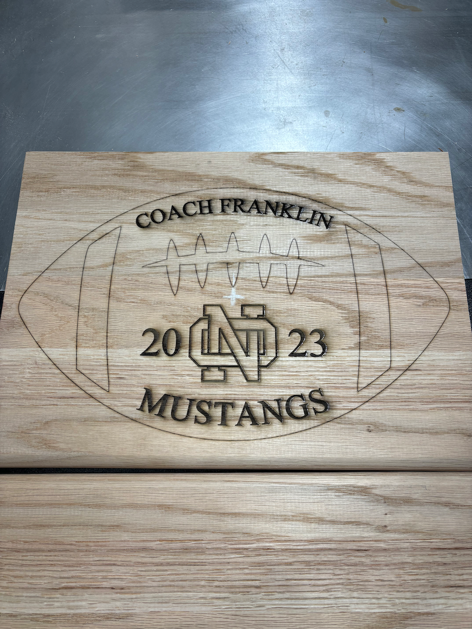 A wooden sign with a football on it that says coach franklin mustangs