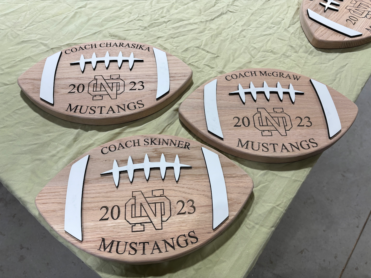 Three wooden footballs with the word mustangs on them