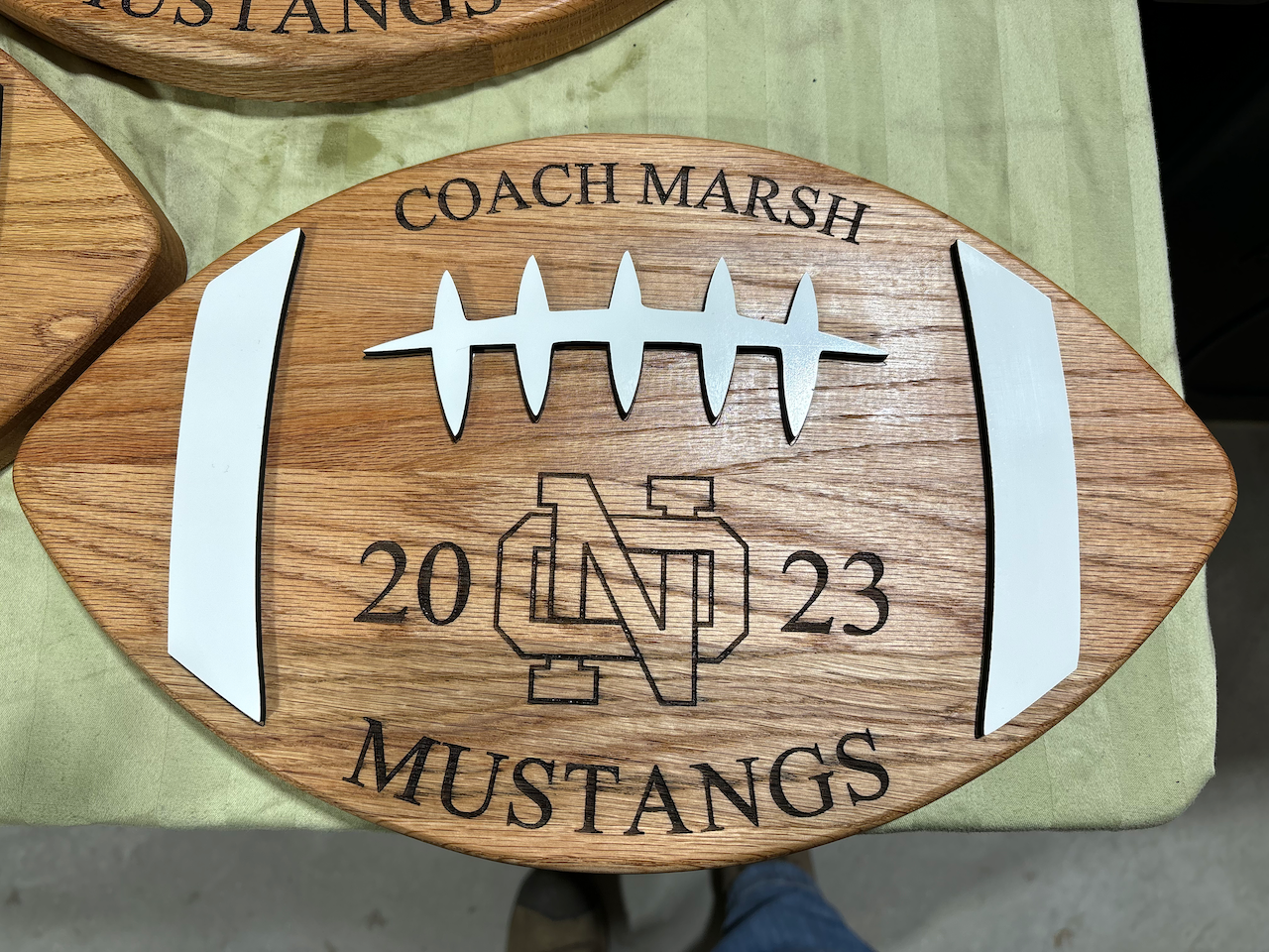 A wooden football with the words coach marsh mustangs on it