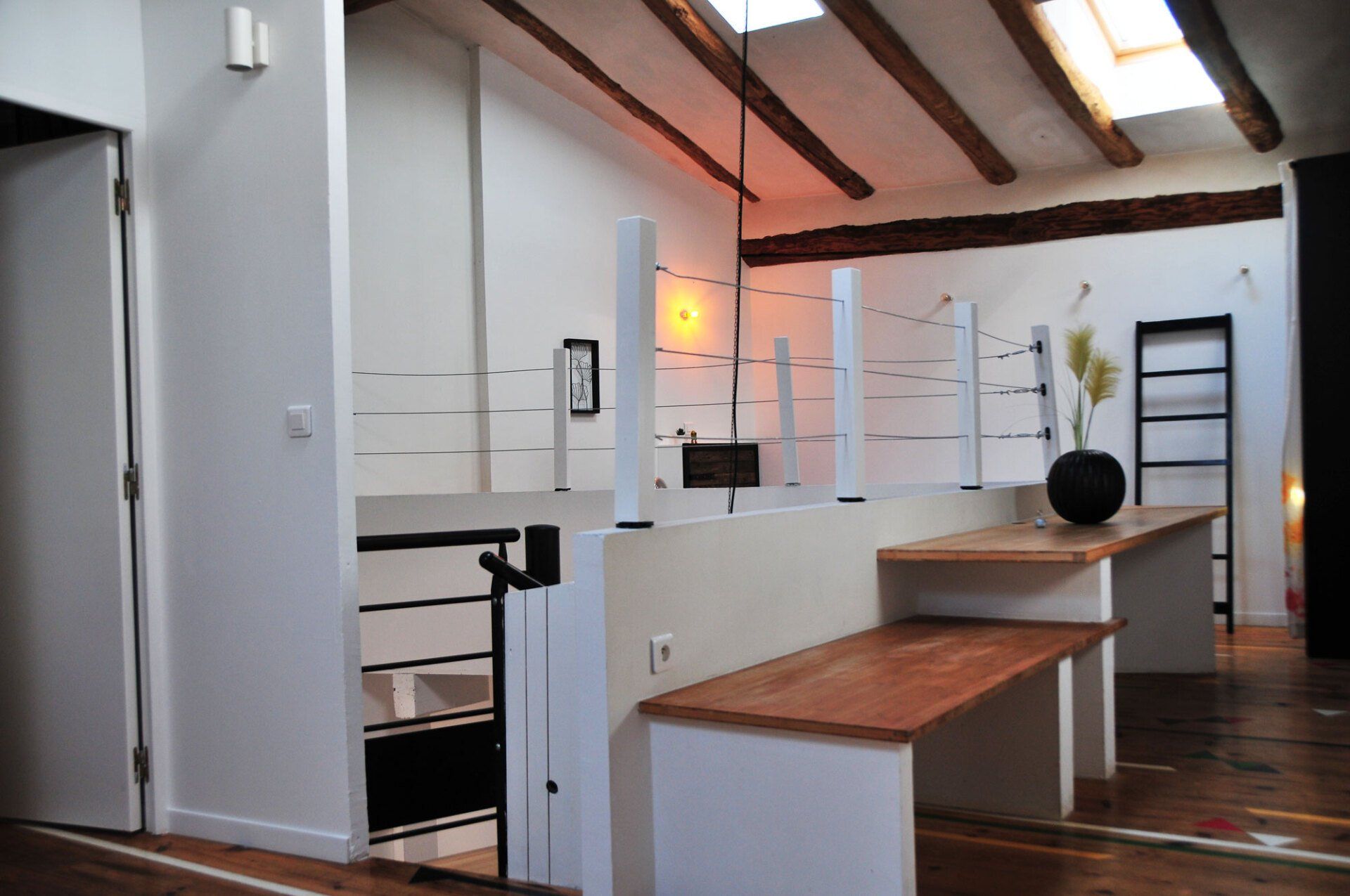 Couloir blanc moderne avec parquet, poutres apparentes, banc et vase de fleurs