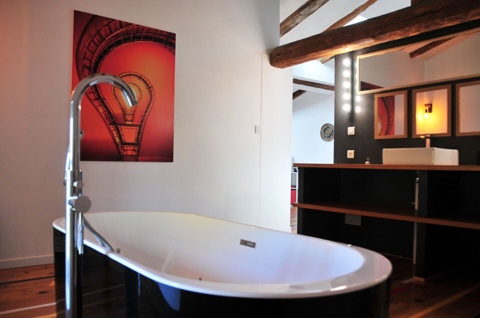 Salle de bains moderne avec baignoire îlot blanche et meuble-lavabo, éclairée par des appliques murales à lumière chaude.