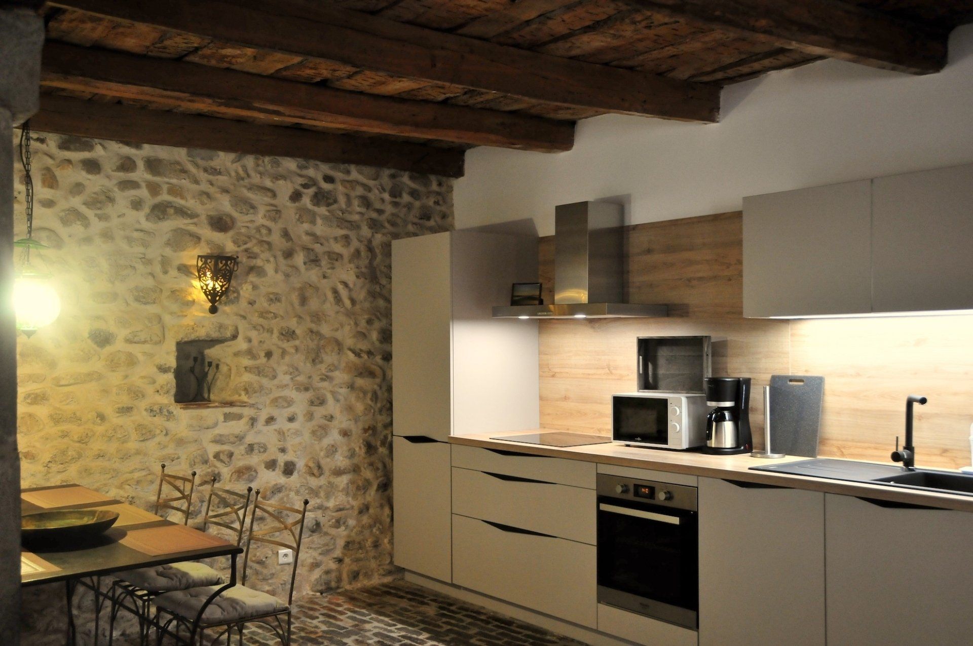 Cuisine rustique avec mur en pierre, poutres en bois et placards et appareils électroménagers modernes
