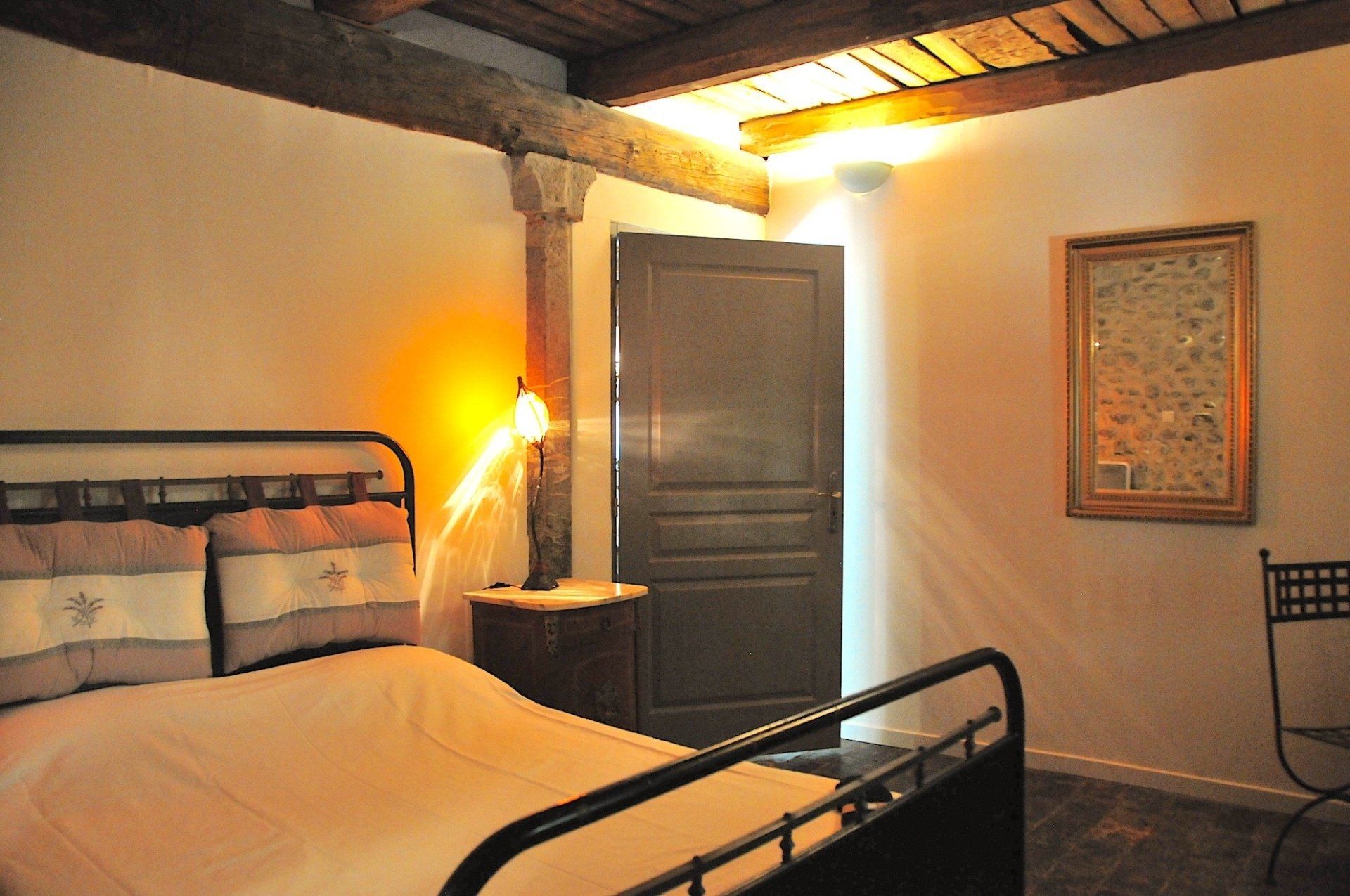 Chambre confortable avec lit en métal, lampe à la lumière chaude, porte sombre et tableaux encadrés au mur