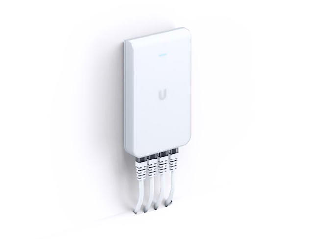 Białe urządzenie sieciowe Ubiquiti zamontowane na białej ścianie, z podłączonymi czterema kablami Ethernet.