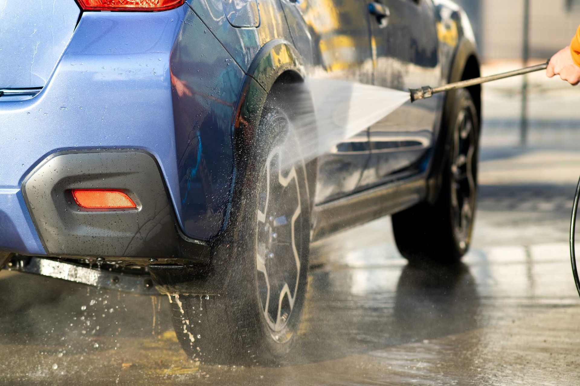 Driver washing his car with contactless high pressure water jet in self service car wash.