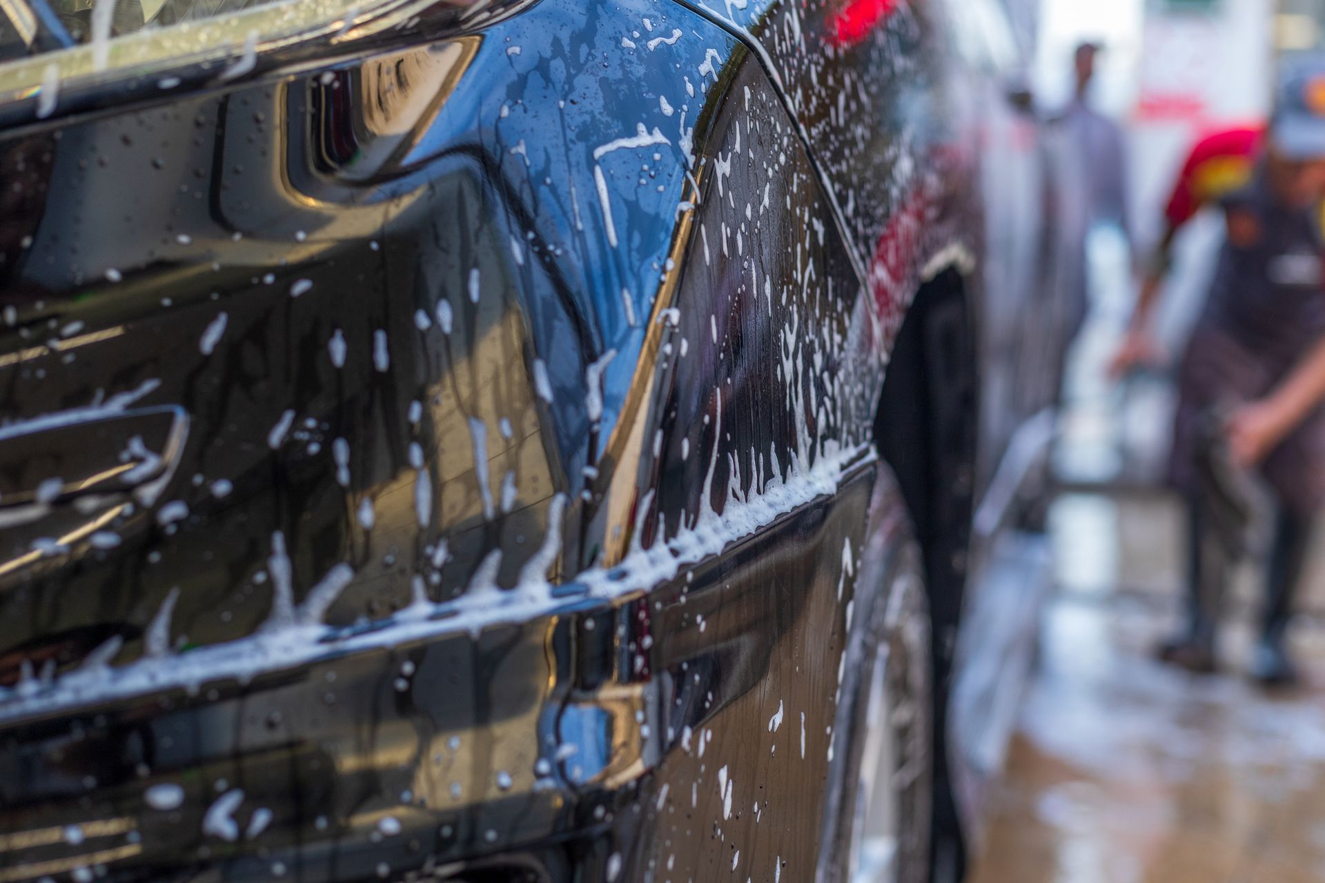 close up of black SUV car headlight cleaning and washing at car wash service station