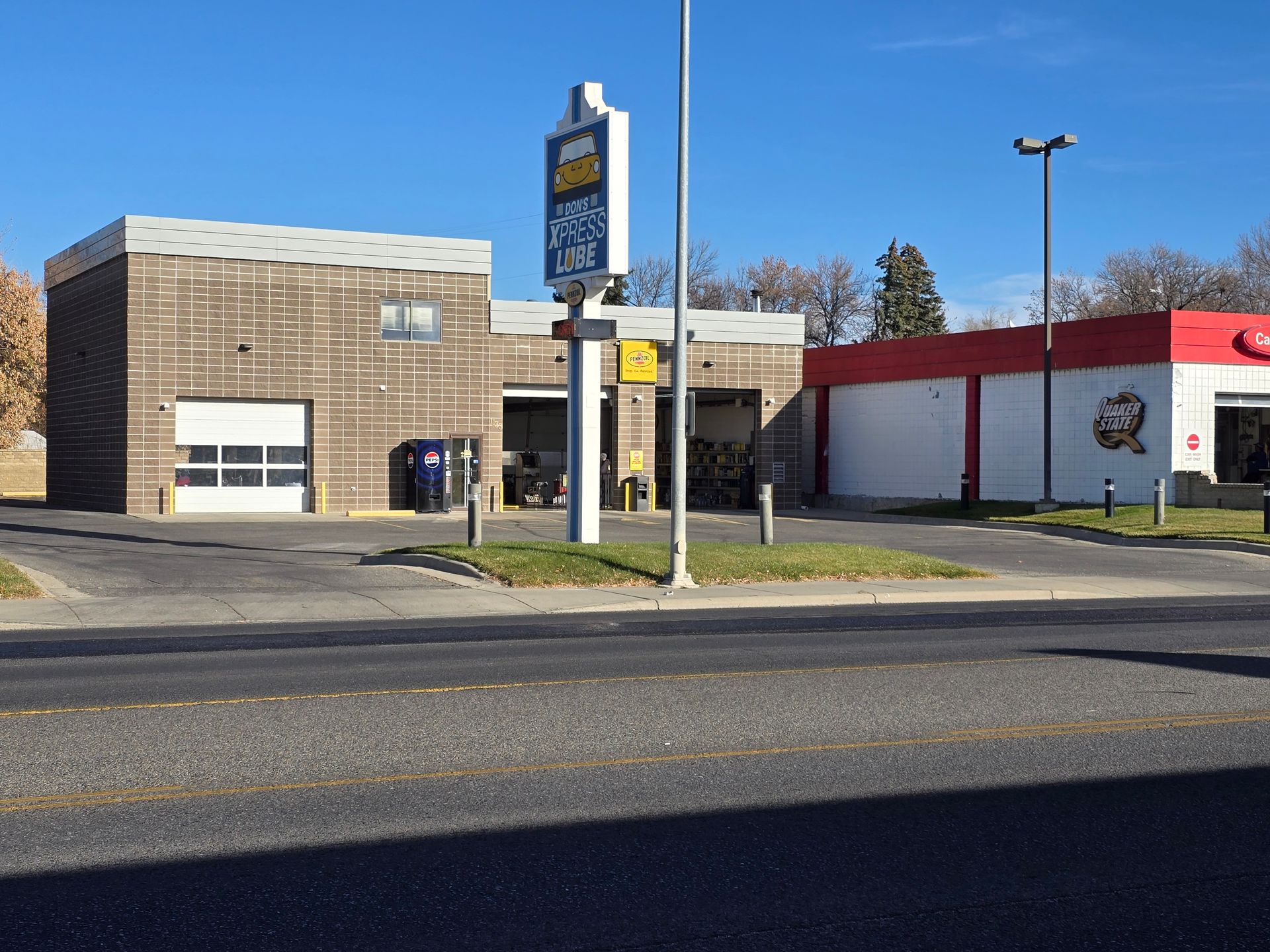 Low brick commercial building and storefronts beside a road on a sunny day