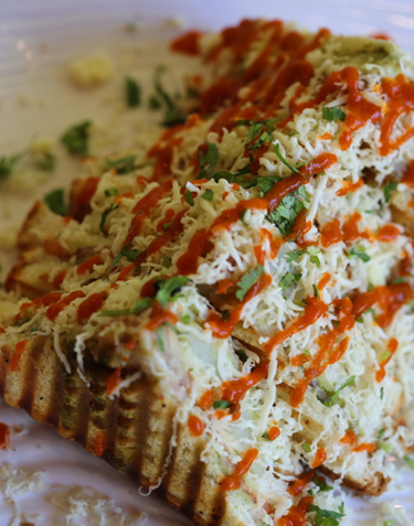 Grilled sandwich with shredded cheese, tomato sauce, and cilantro.