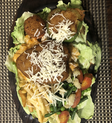Dish of food: fried items, vegetables, cheese, and french fries on lettuce.