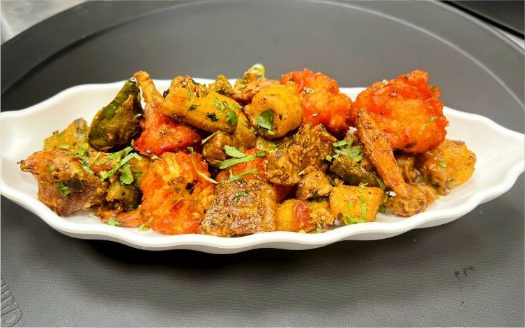 A white serving dish filled with colorful, fried vegetables, garnished with herbs.
