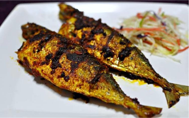 Two fried fish on a white plate with a side of coleslaw.