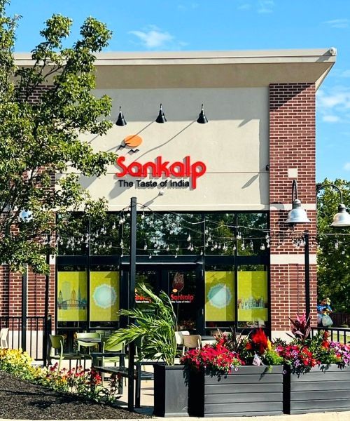Sankalp Indian restaurant exterior with red sign, flowers, and brick facade.