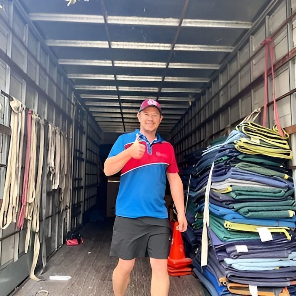 A Man Is Standing in The Back of A Truck Giving a Thumbs Up — Novocastrian Removals & Storage in Cardiff, NSW