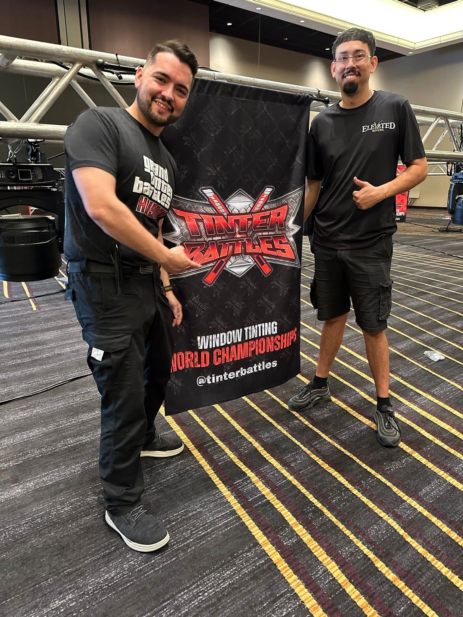 Two men hold a vertical banner with 