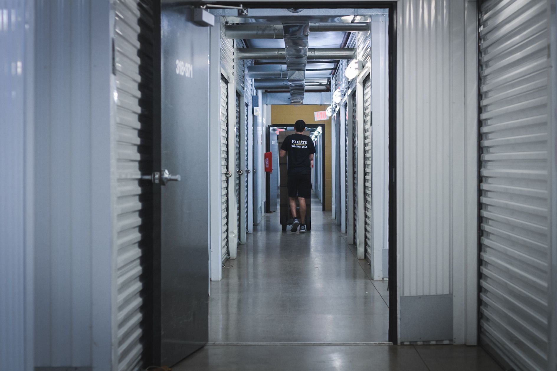 Storage unit hallway; person pulling a cart, other storage units on either side.