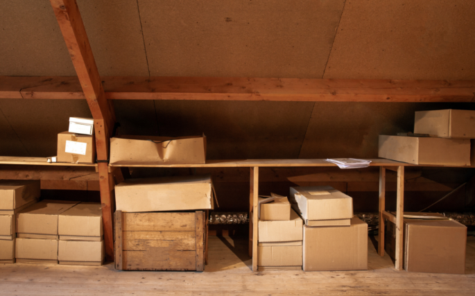 Boxes stored on shelves in a dimly lit attic.