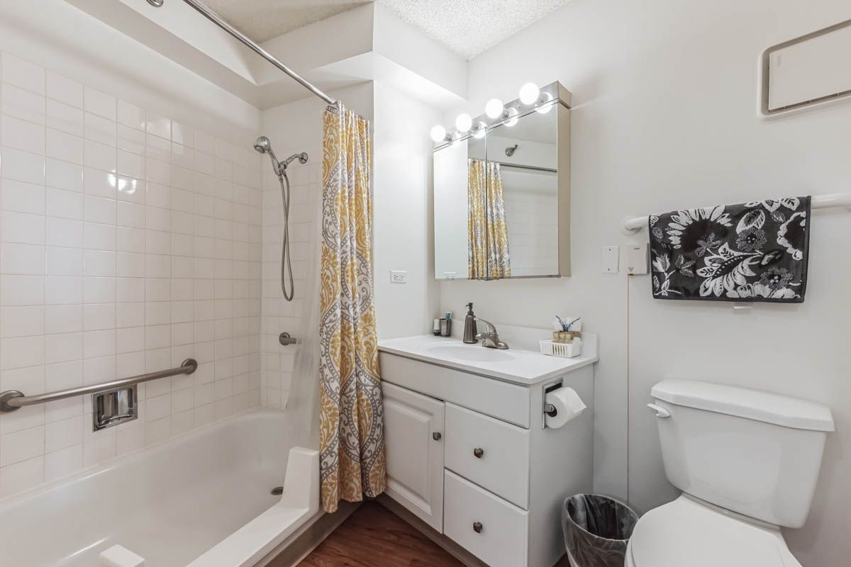 A bathroom with a tub , sink , toilet and mirror.