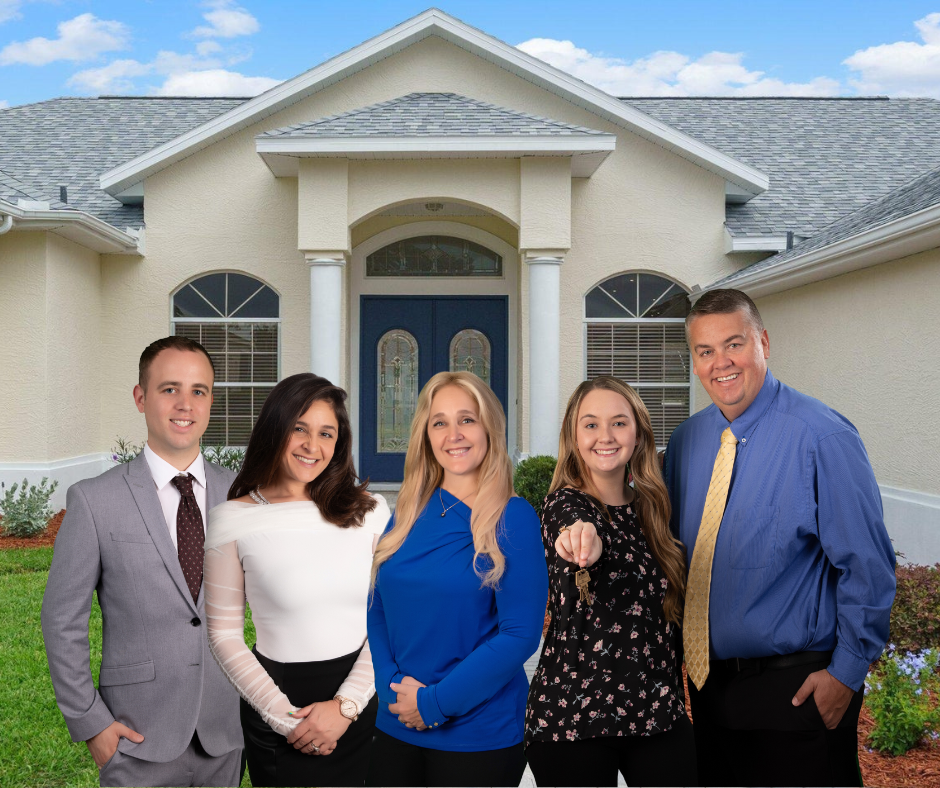 Three Female Realtors with arms crossed and Male Realtor center holding a for sale sign.